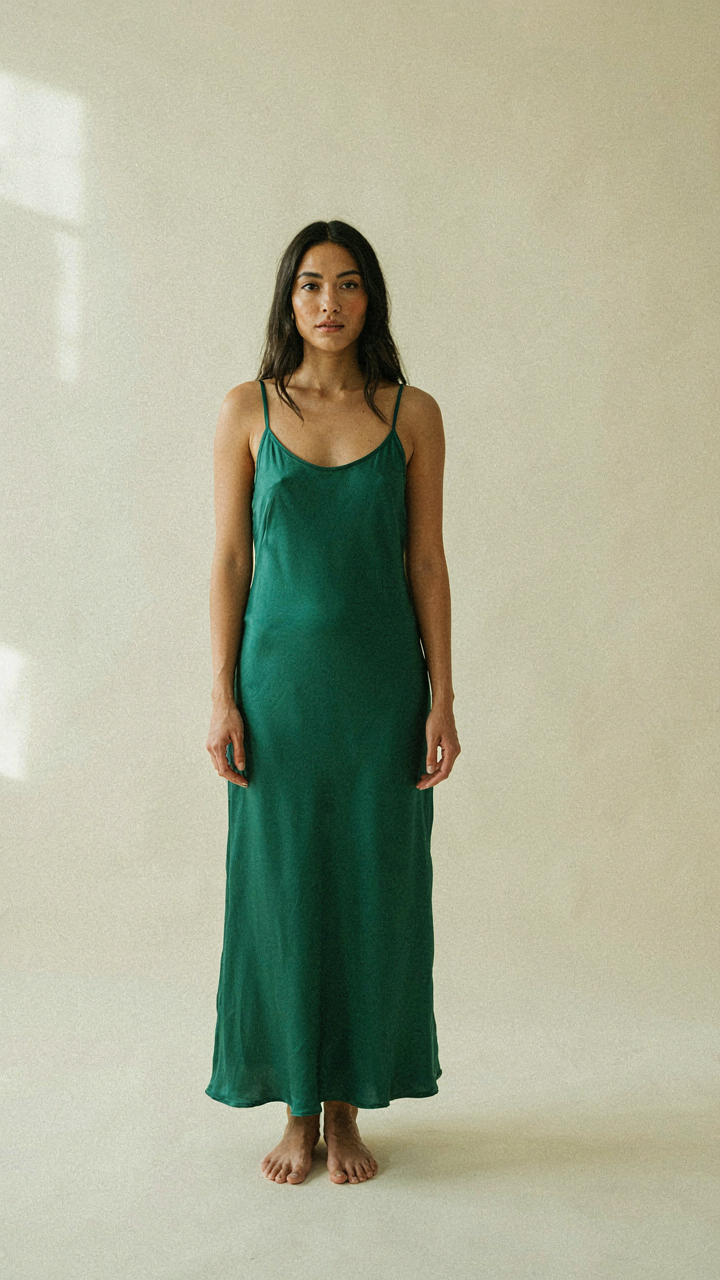 Woman in a long dress stands with confident posture, shoulders back.