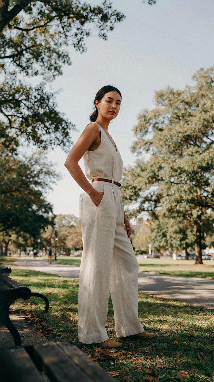 Woman in a jumpsuit angled in a park, showing space around her body.