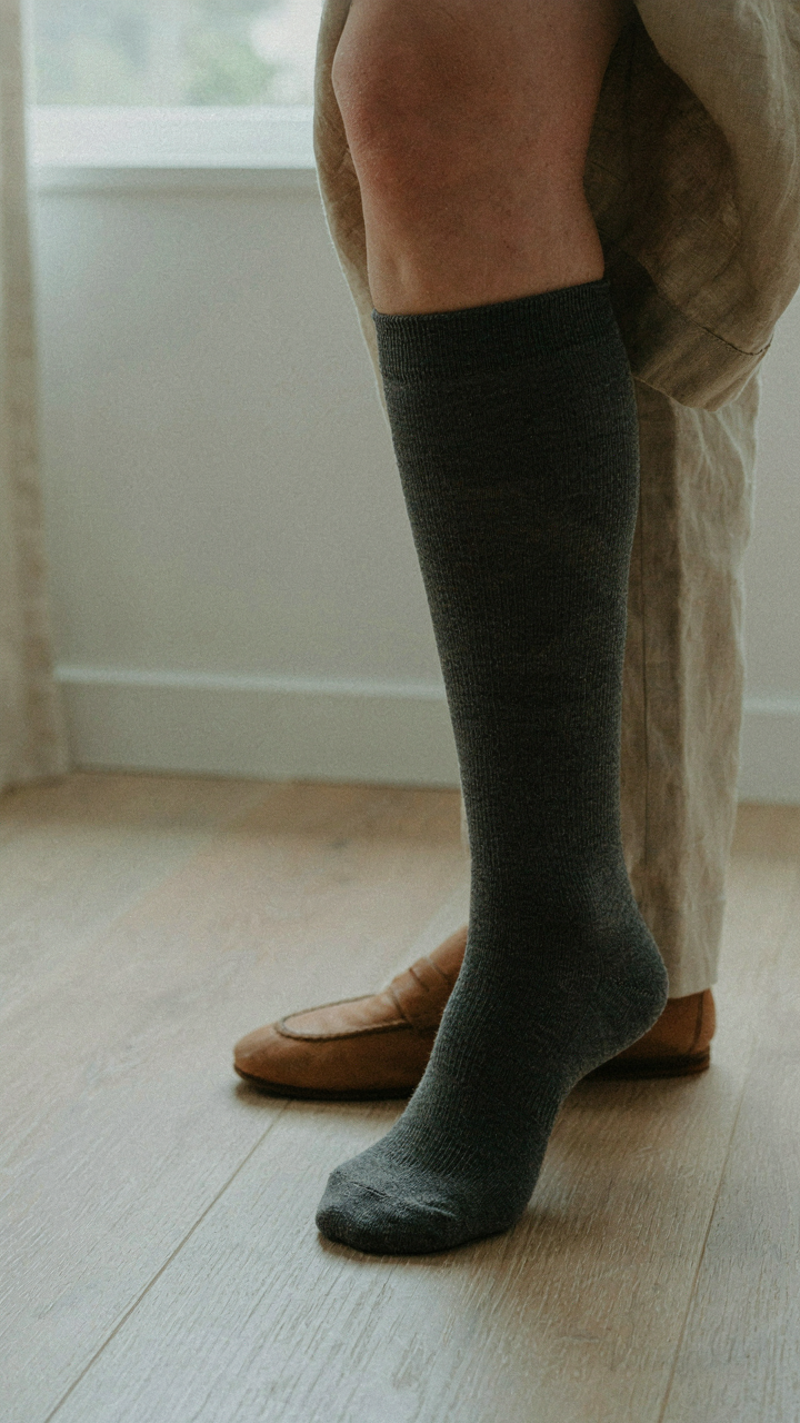 Woman wearing a knee-high compression sock for circulation on a long flight.