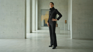 Woman in a structured jumpsuit in a modern gallery, embodying creative black tie attire.