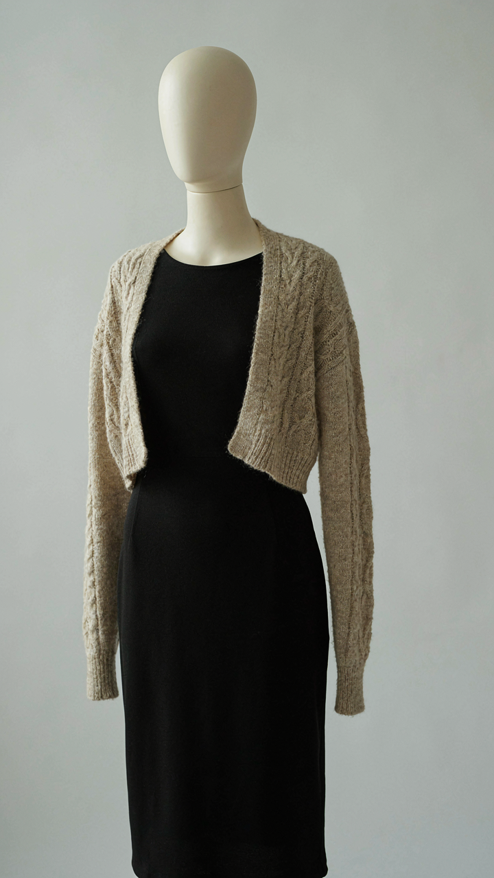 Cropped cardigan creating a horizontal line over a black cocktail dress.