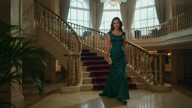 Woman in an elegant gown walking down a grand staircase on a cruise ship.