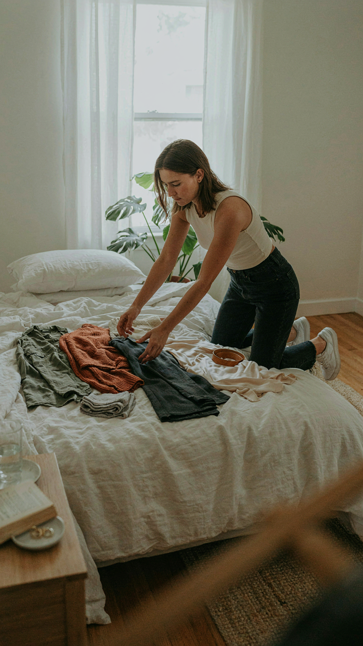 A person lays out clothes on a bed, testing different outfit combinations.