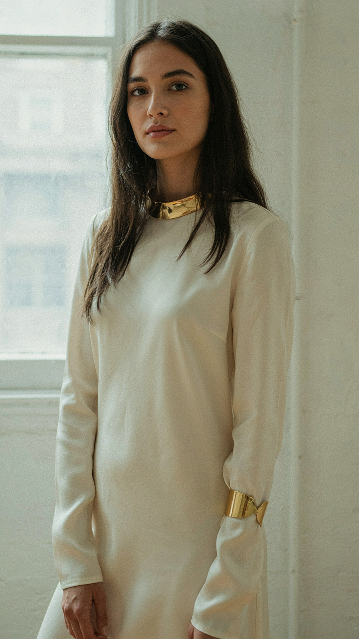 A woman in a long sleeve dress wearing a bold necklace and bracelet.