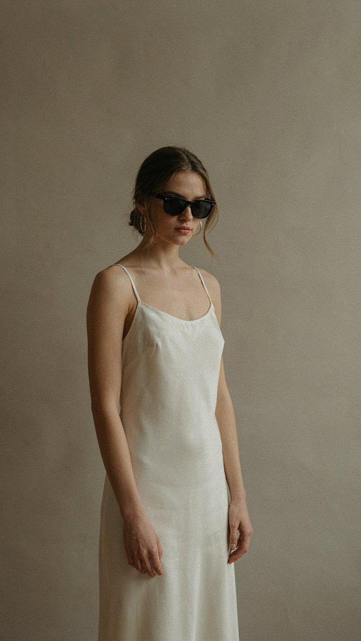 A person in a timeless wedding guest outfit wears classic black Wayfarer sunglasses.
