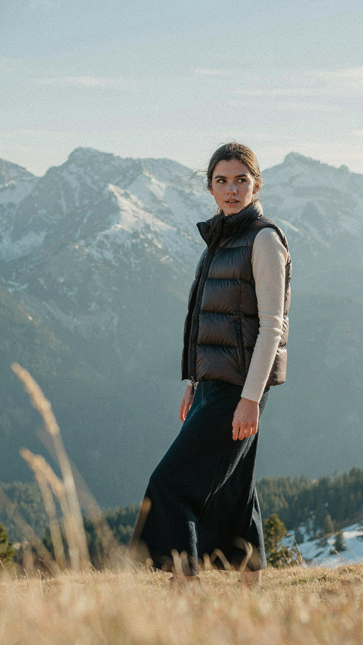 A fitted puffer vest is worn over an elegant dark dress.