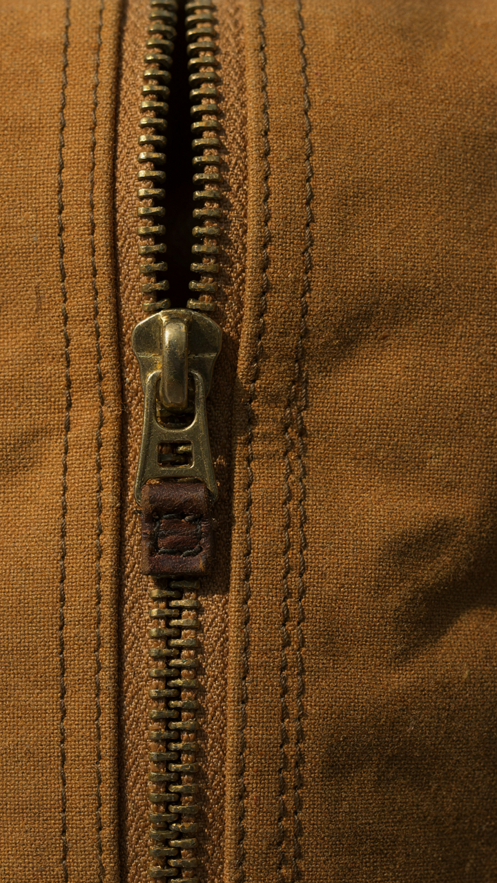 A close-up shows a strong metal coil zipper on a travel bag, built to last.