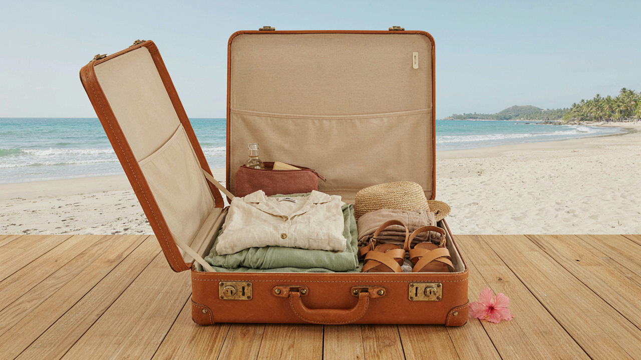 An open suitcase filled with warm weather clothes for a destination wedding guest.