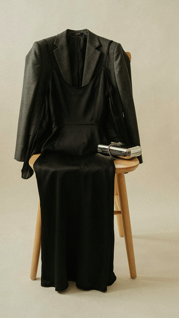 A black gown, metallic clutch, and blazer on a chair.