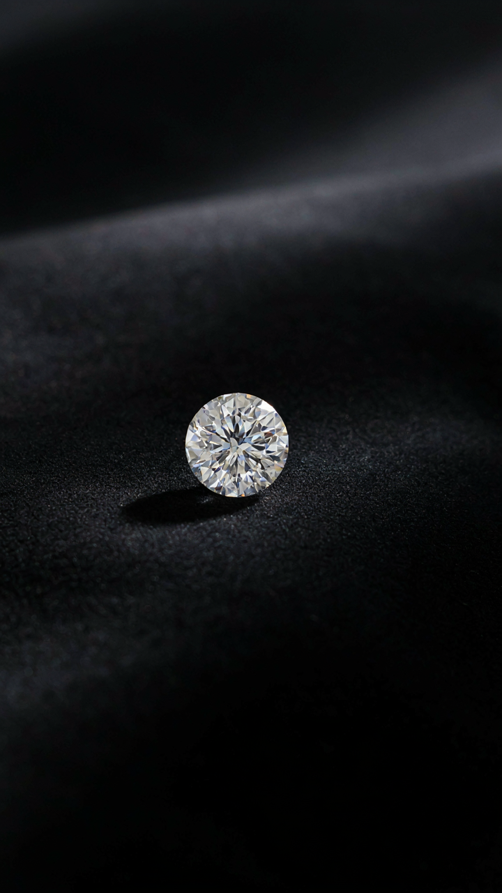 A single, sparkling diamond sits on a piece of black velvet.