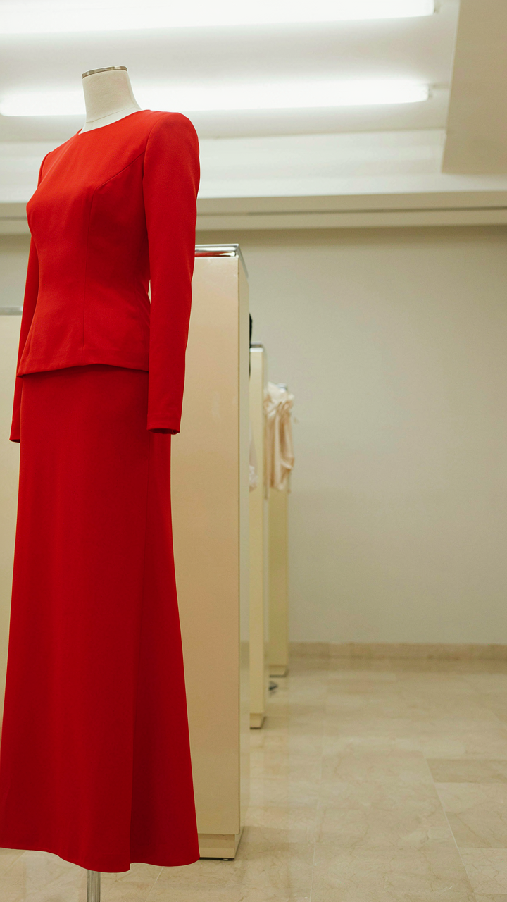 A vibrant red structured evening gown on a mannequin.