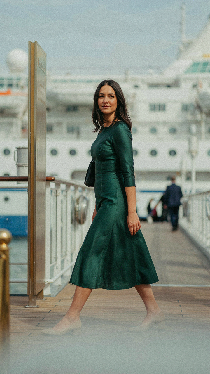 Woman in a midi dress walks past a cruise dress code sign.