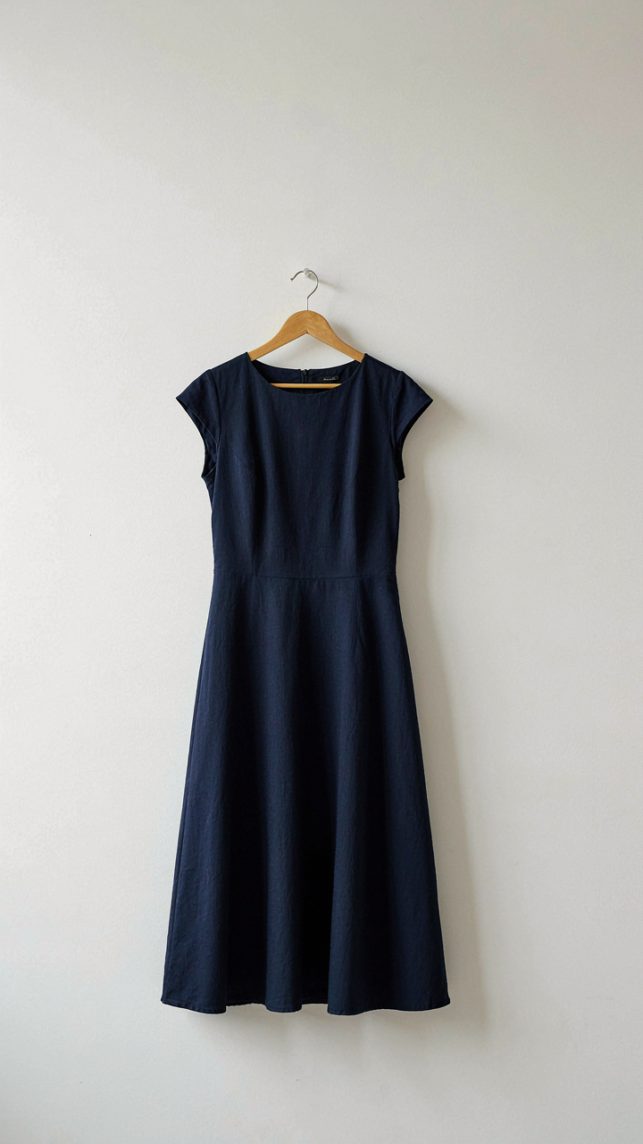 A classic navy blue A-line dress hanging neatly on a wooden hanger.