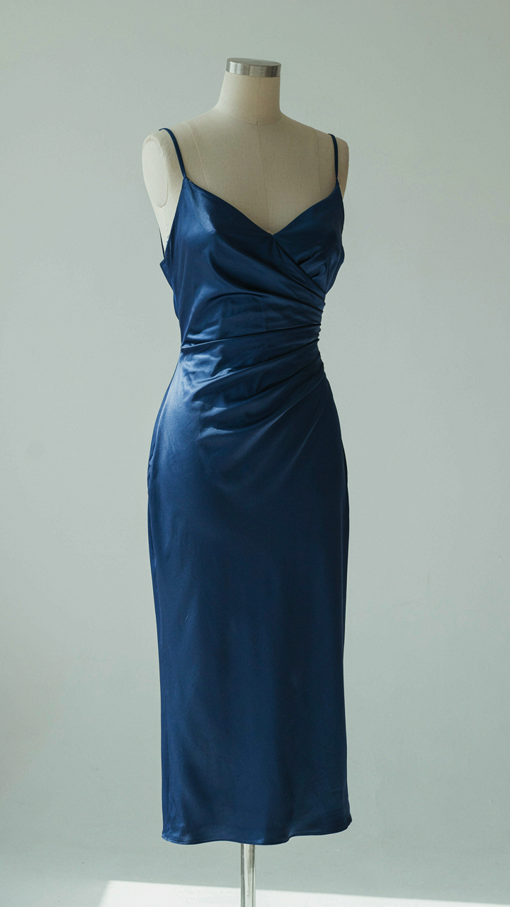 A sapphire blue bias-cut satin cocktail dress on a mannequin.
