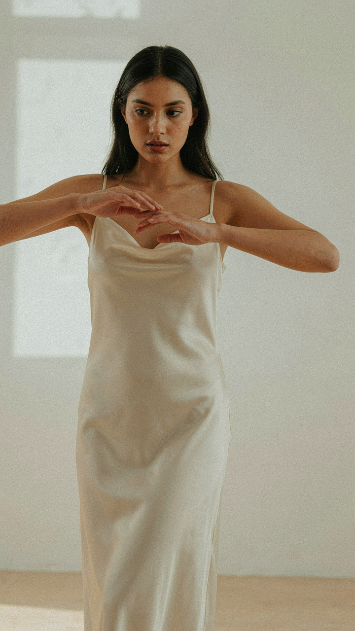 Hands gently touch flowing silk fabric, showing its natural sheen.