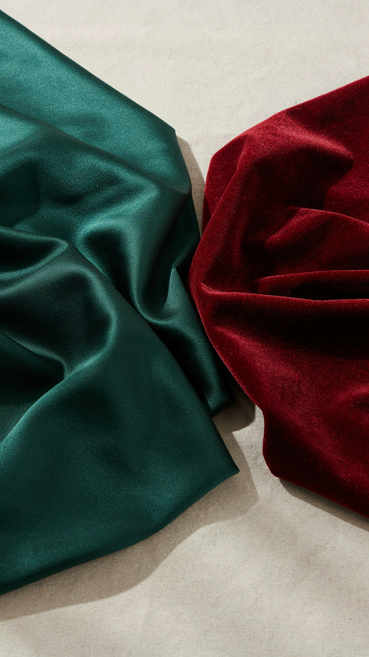 Swatches of shimmering silk charmeuse and rich velvet fabric, reflecting and absorbing light.