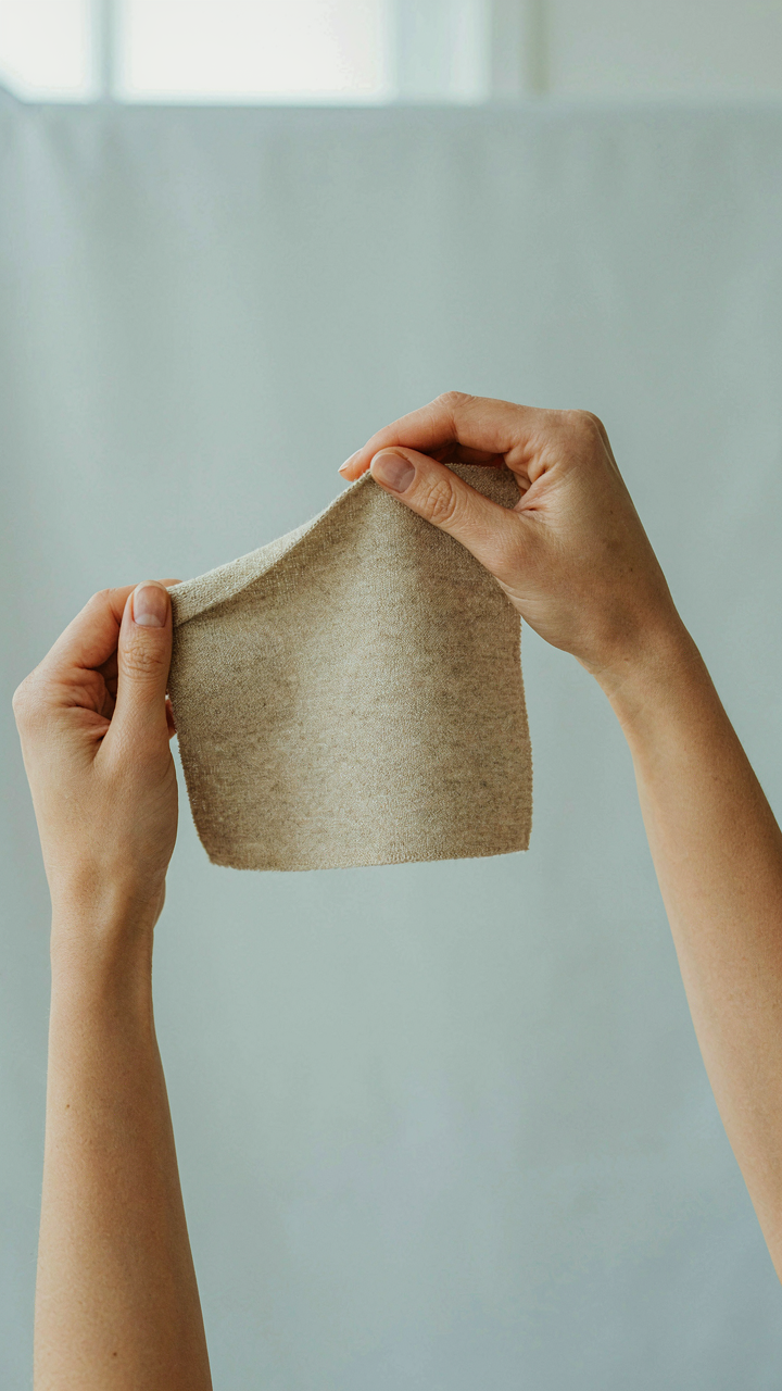 A hand performing a touch test on a piece of high-quality wool fabric.