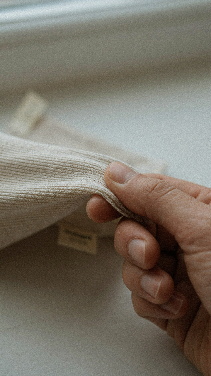 A hand stretches fabric, showing its elasticity and ability to snap back.