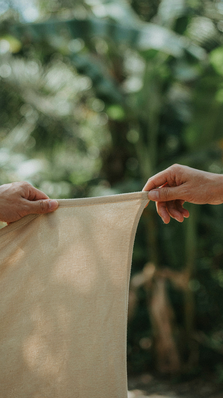 A hand stretches a piece of lightweight, breathable performance fabric for a tropical wedding guest