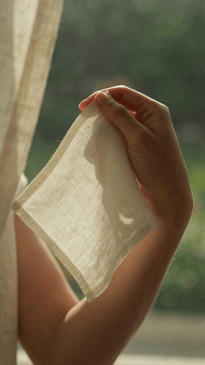 Hand holds lightweight cotton voile fabric in direct 2 PM sunlight.