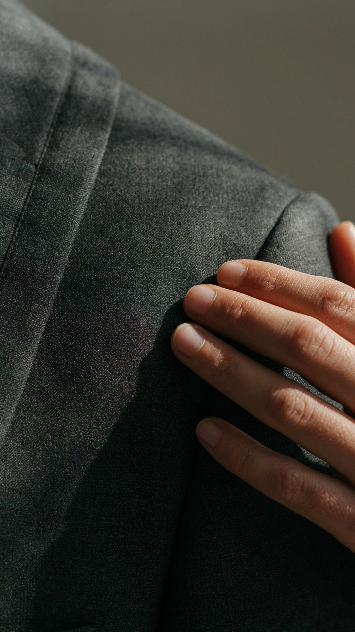 Hands are gently touching expensive wool fabric on a tailored pantsuit.