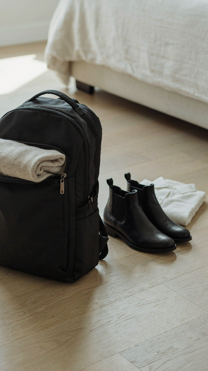 A compact travel backpack with Chelsea boots, sweater, and shirt for efficient packing.