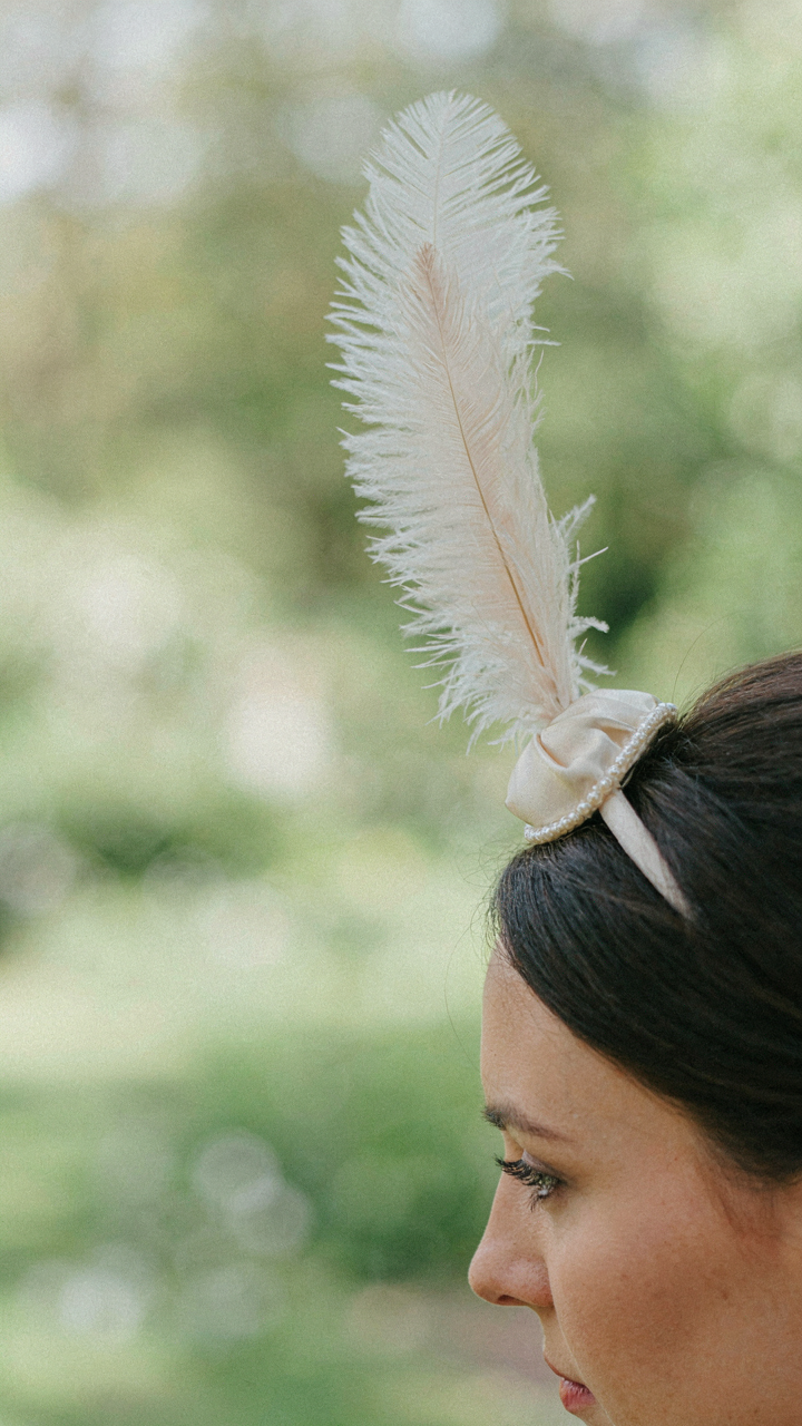 A close-up of a fascinator with a single tall ostrich plume.
