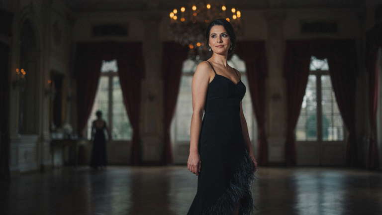 A confident woman in a black feather trim dress in a grand ballroom.