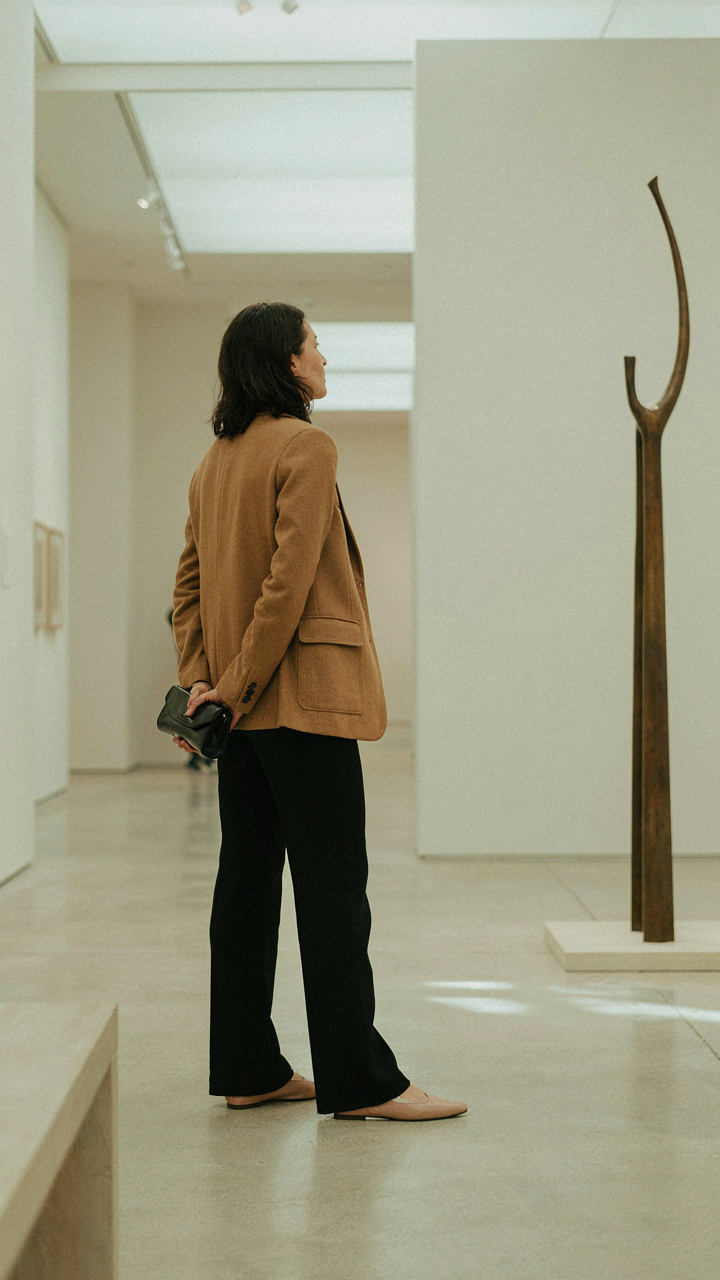 A woman in a stylish dressy casual outfit looks at art in a gallery.