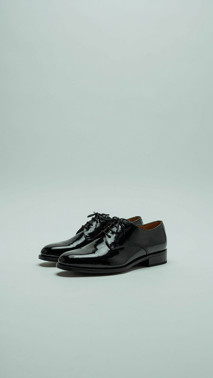 Highly polished black patent leather dress shoes on a clean floor.