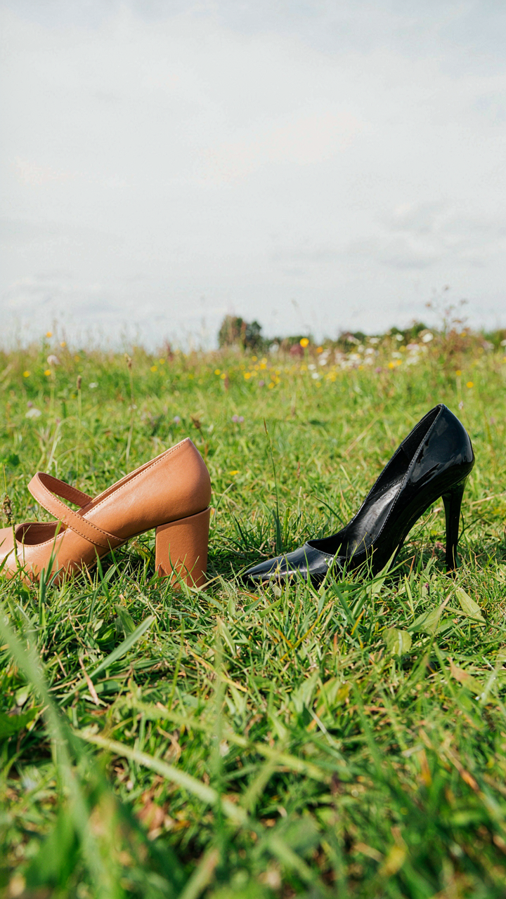 A block heel stands firm on grass while a stiletto sinks, illustrating stable footwear.