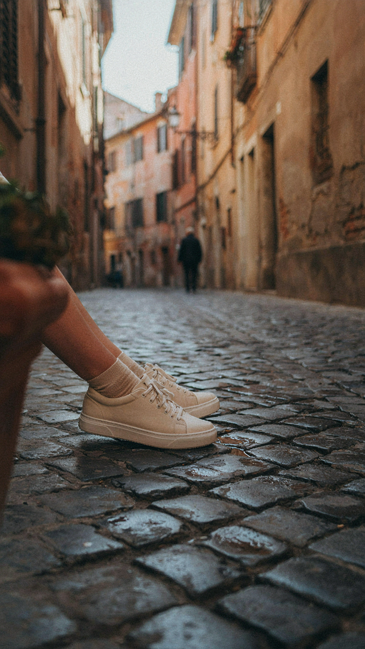 A woman's feet in comfortable walking shoes on a cobblestone street.