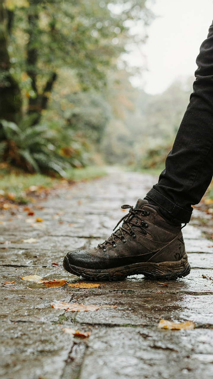 A waterproof boot with deep treads grips a wet stone path, preventing slips.