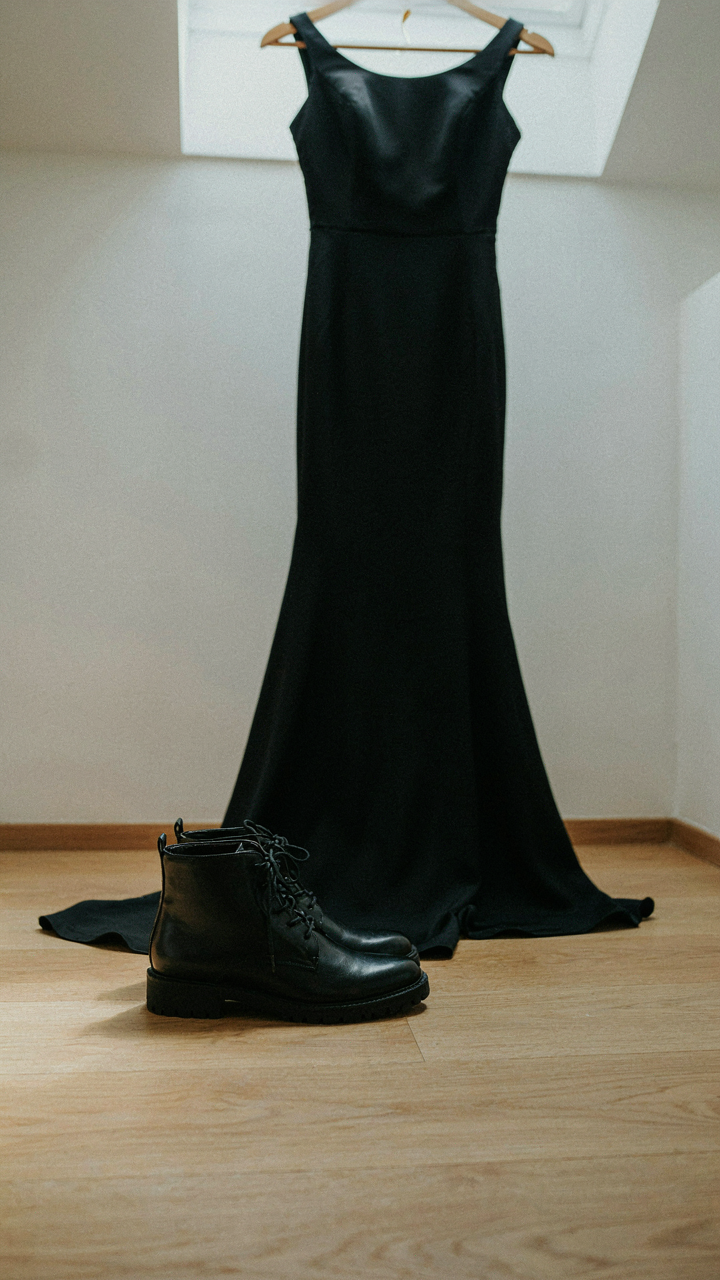 Close up shows a formal black boot with a textured rubber sole next to a dress.