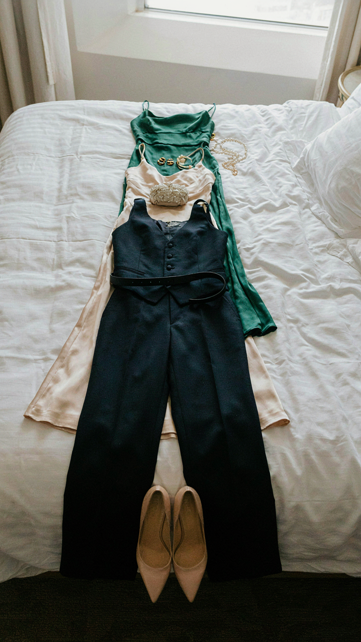 Three formal outfits laid out on a bed with one pair of heels.