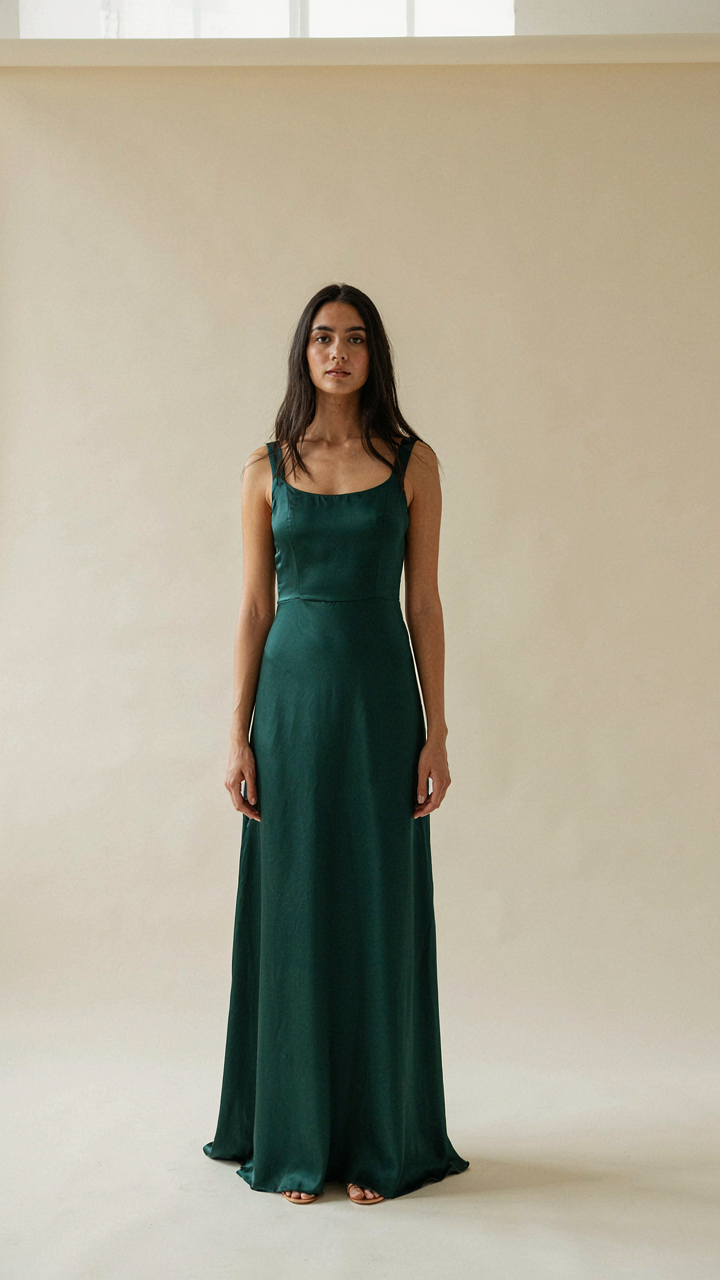Woman in a formal long dress stands with elegant and poised posture.