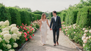 A well-dressed couple walks in a formal garden, illustrating formal garden wedding dress code.