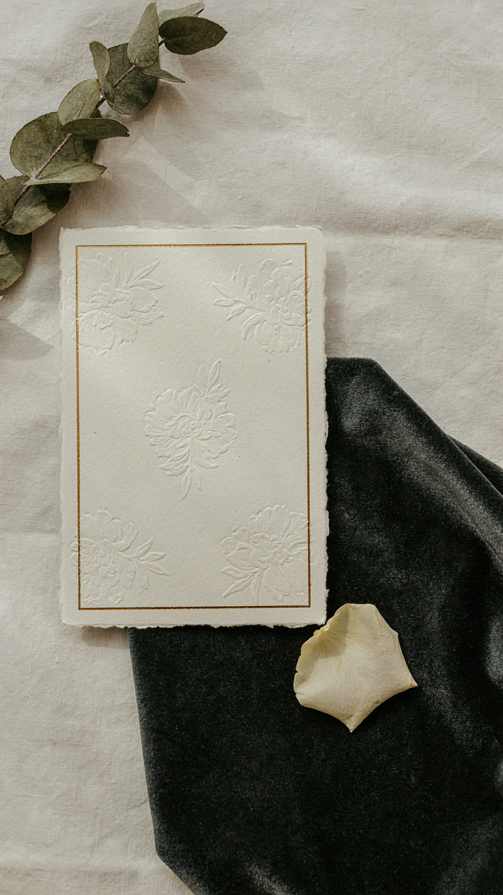 A wedding invitation rests next to a swatch of luxurious dark fabric.