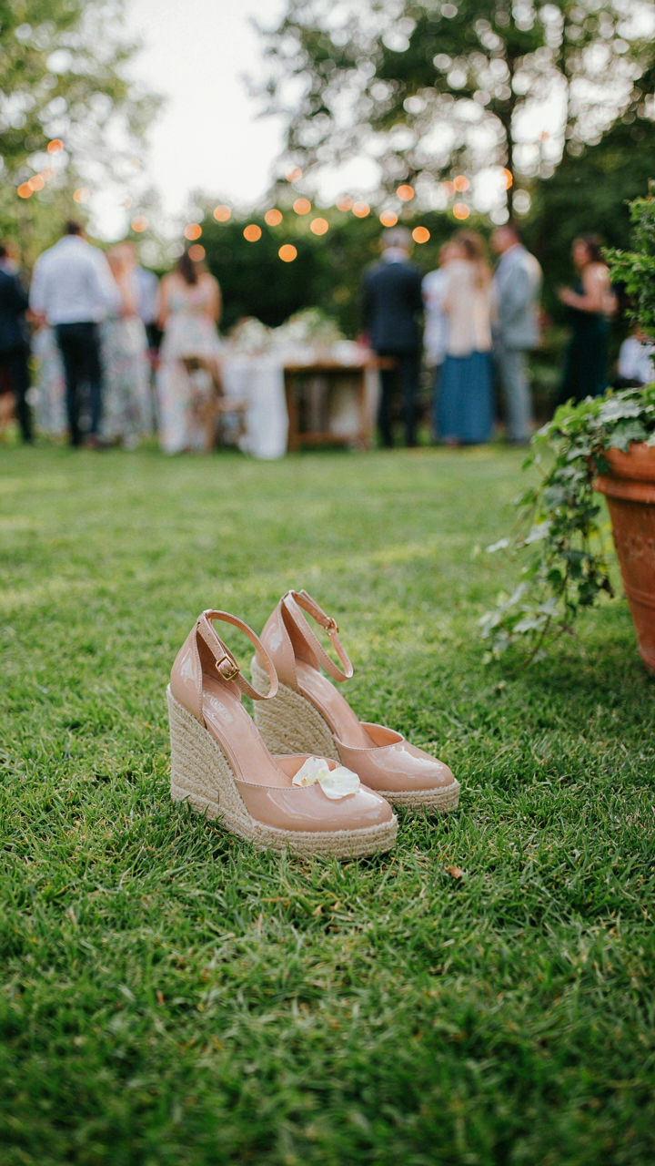 Wedge heels with thick soles rest on a well-maintained lawn at a garden party.