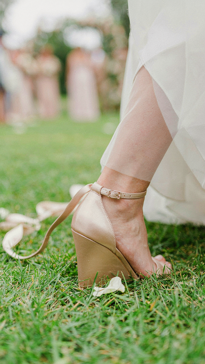 A woman's wedge heel sinking slightly into soft grass.