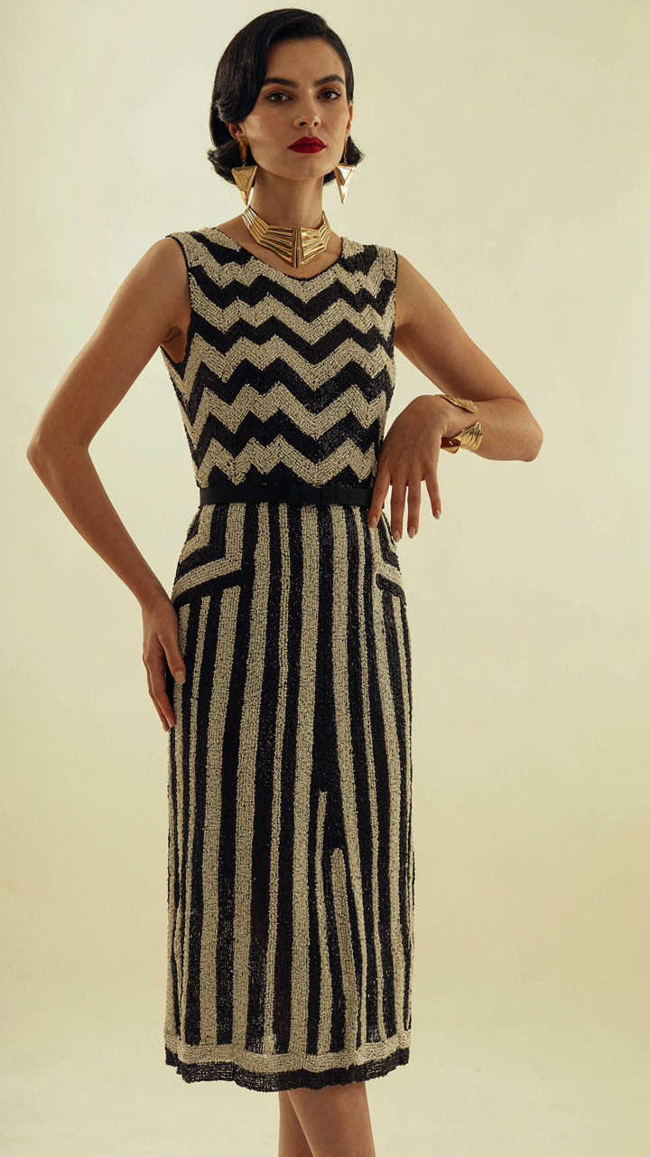 A woman in an Art Deco beaded dress, with sleek hair and angular jewelry.