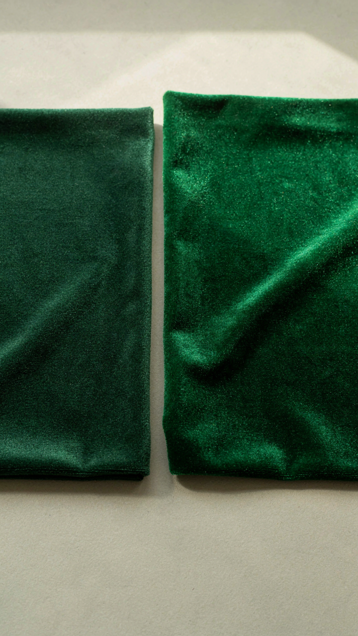 Two swatches of velvet fabric, one standard green, one emerald green.