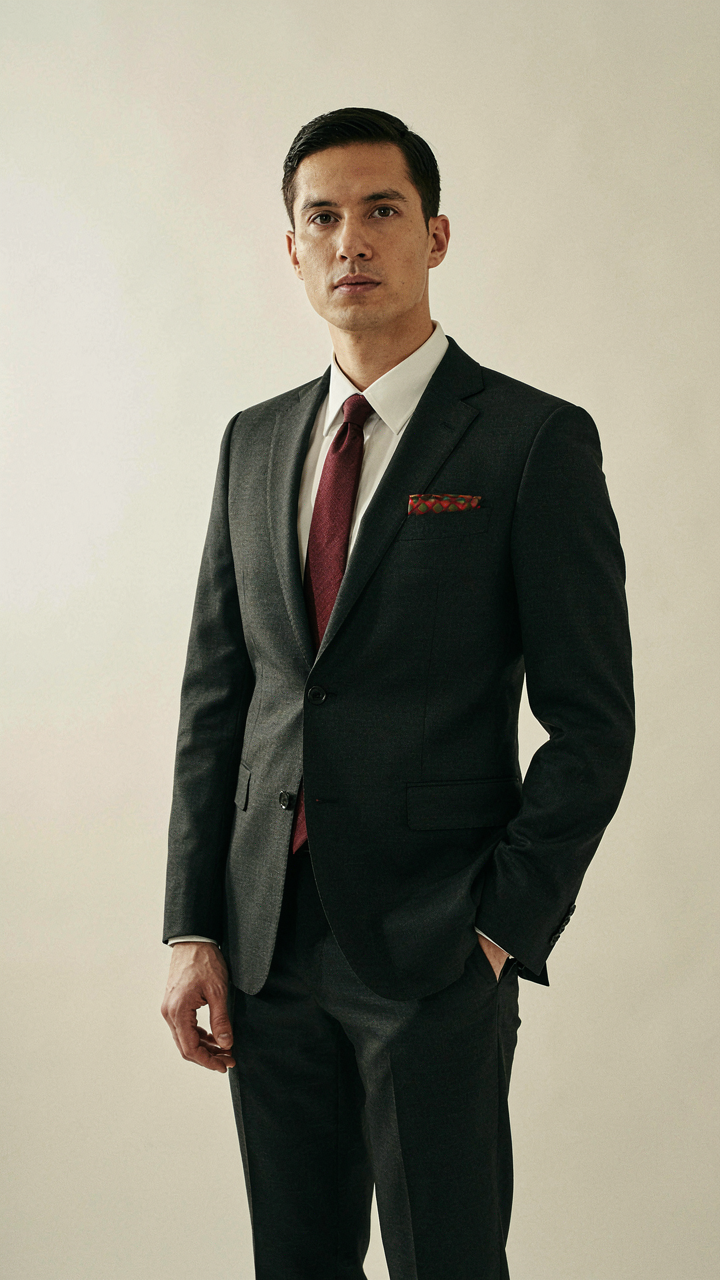 A dark charcoal suit with a burgundy tie and a single festive pocket square.