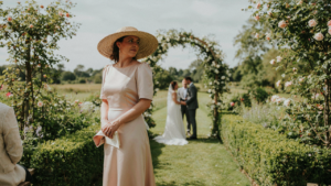 A woman in a stylish hat for wedding guest outfit, in a garden.