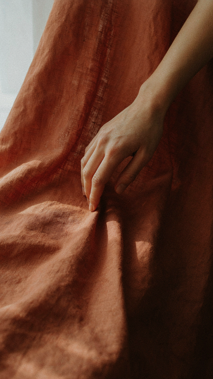 Close-up of naturally wrinkled terracotta linen fabric, showing texture.