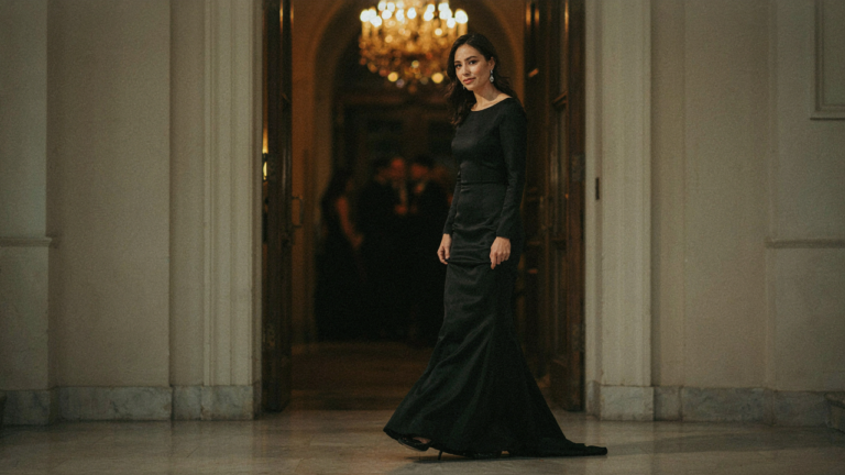 Woman in a black dress wearing elegant jewelry at an evening event.