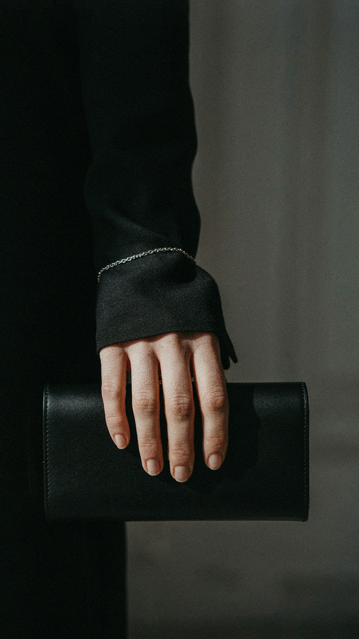 A woman's hand with a silver bracelet and a black clutch, perfect jewelry for black dress.