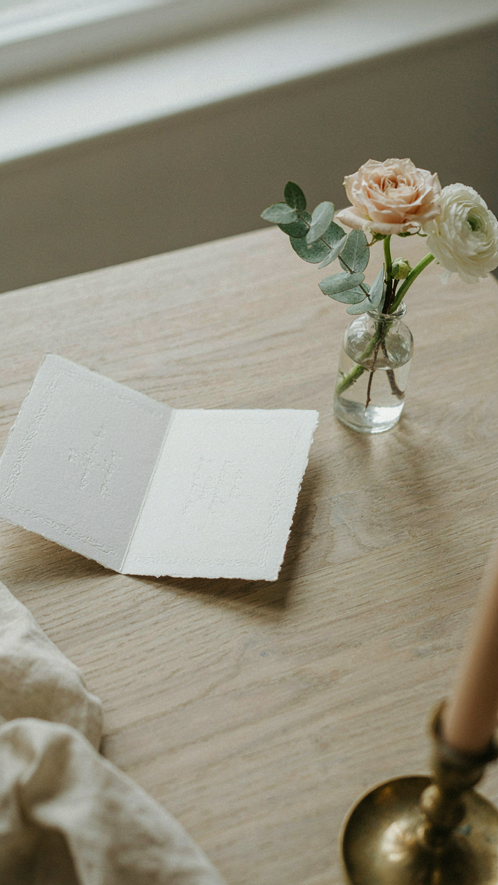 An elegant invitation card lies open next to flowers.