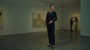 A woman wears a dark blue jumpsuit with sleeves in an art gallery.