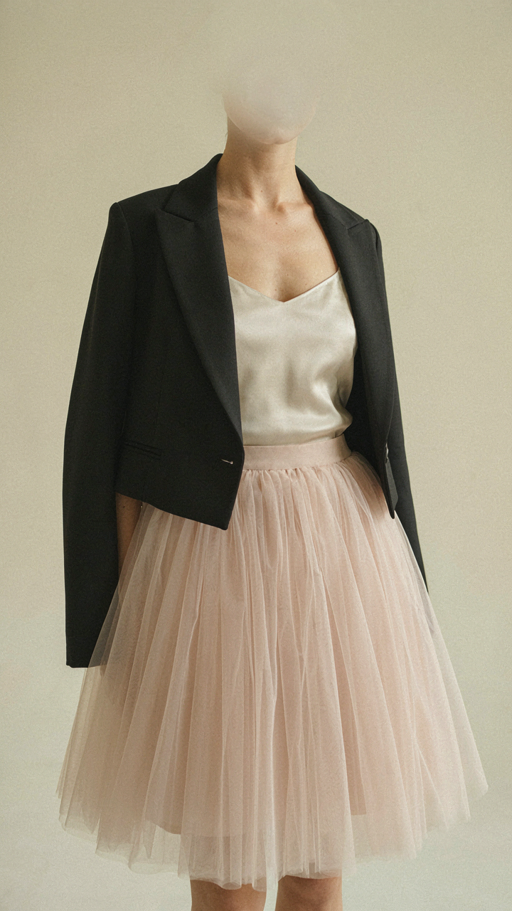 A woman wears a satin camisole, cropped blazer, and a full tulle skirt.